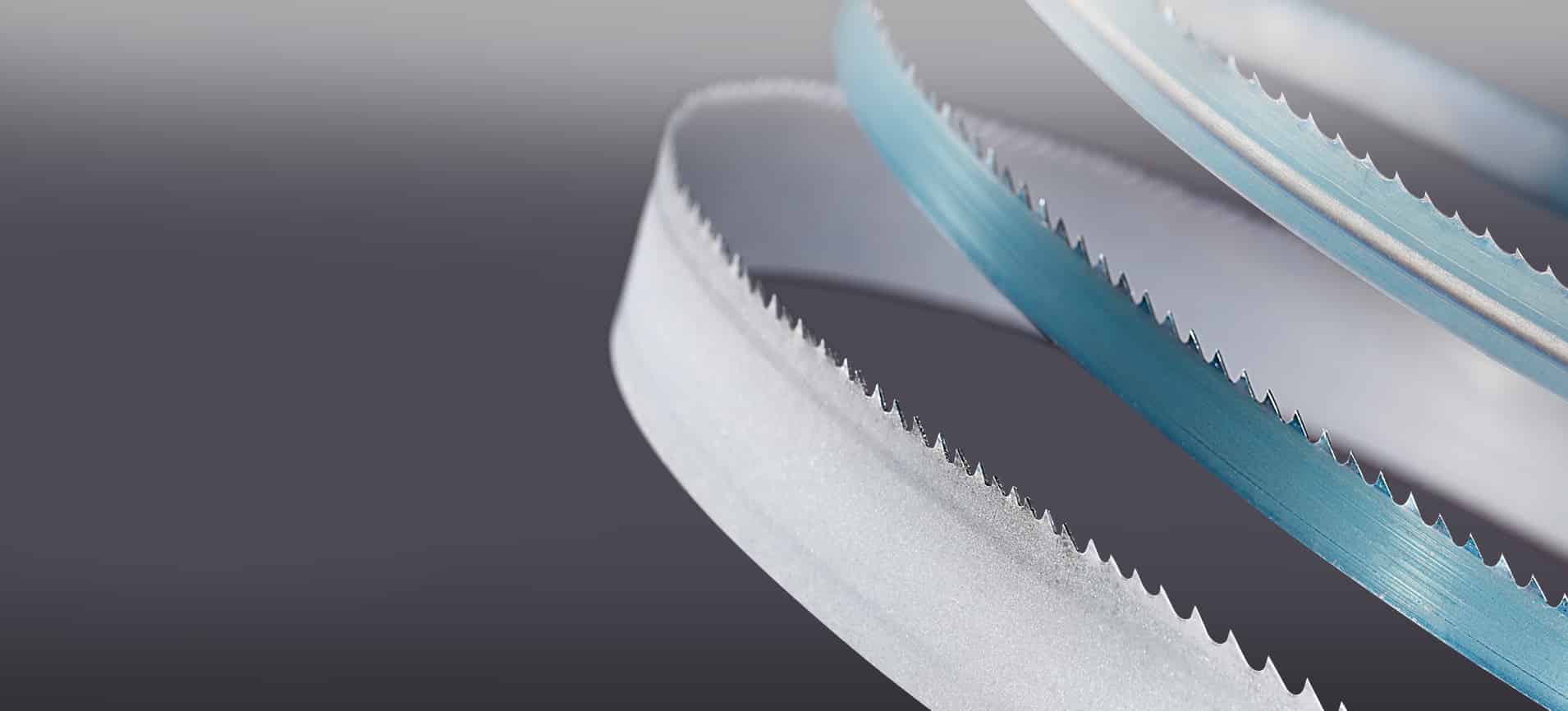 Simmons' metal cutting bandsaw blades curve and catch the light against a dark gray background.